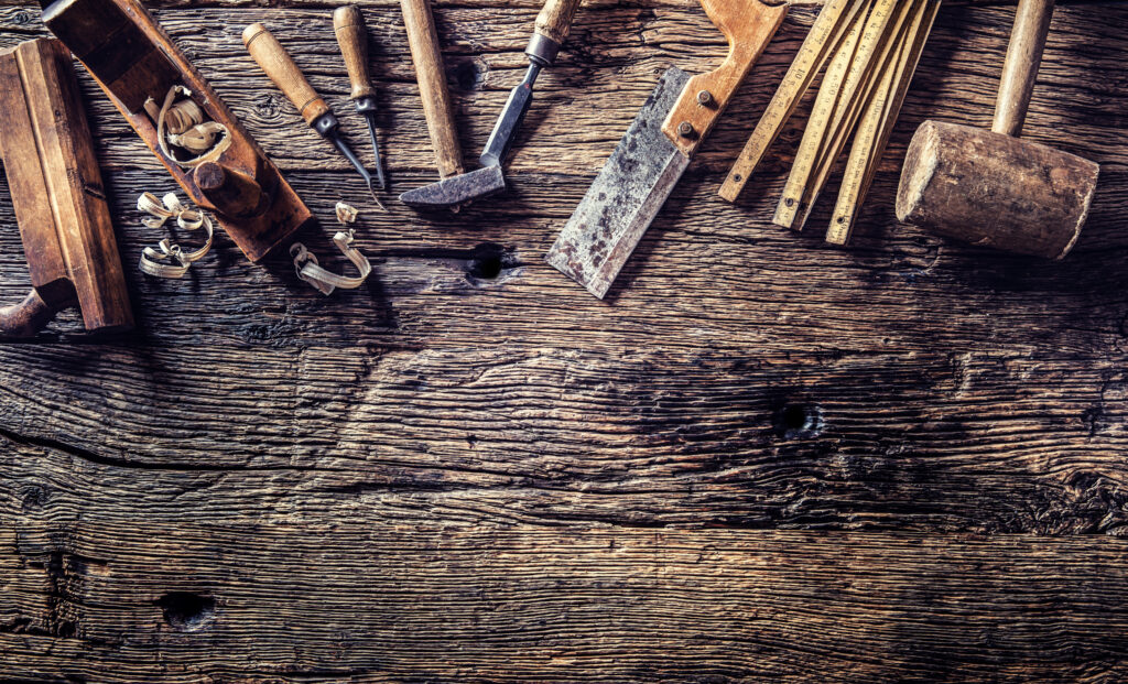 Assorted hand tools arranged on a weathered wooden workbench