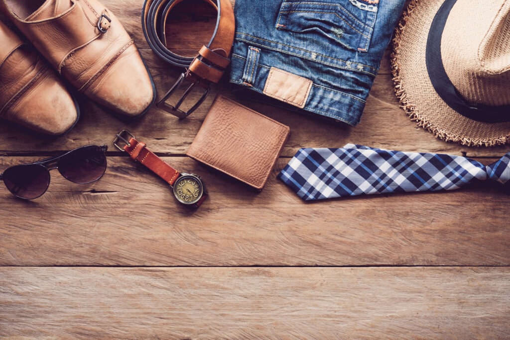 Everyday accessories including leather shoes, belt, wallet, watch, sunglasses, and folded clothing
