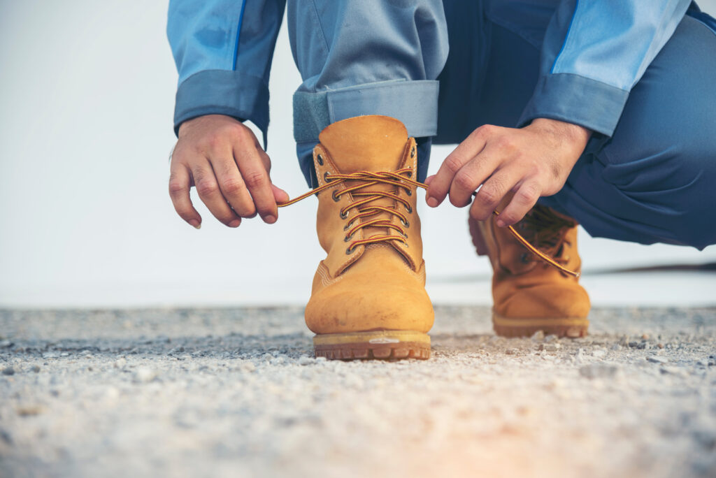 Person tying the laces of sturdy work boots outdoors